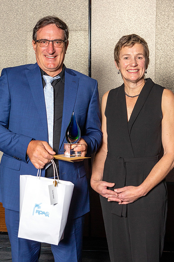 Middle aged couple holding award with gift bag smiling