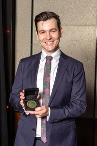 Man holding award while smiling